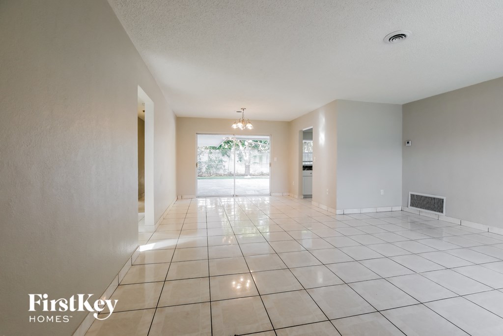 an empty living room with a large tiled floor and a door to a garage
