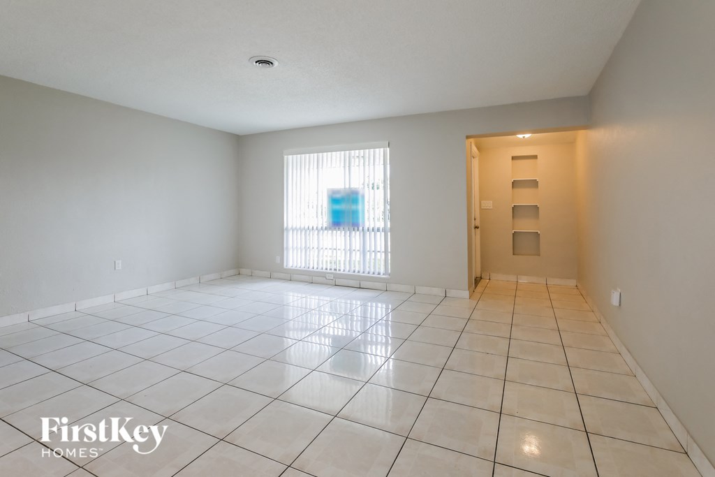 an empty living room with tiled floors and a door to a closet