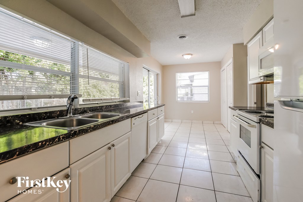 a kitchen with white cabinets and black counter tops and a sink