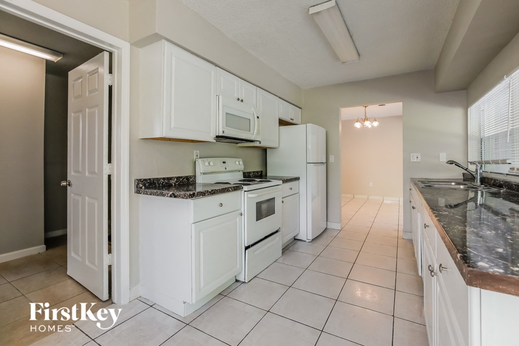 a kitchen with white cabinets and appliances and a counter top