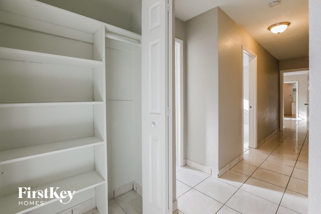 a walk in closet with white shelves and a hallway with a door