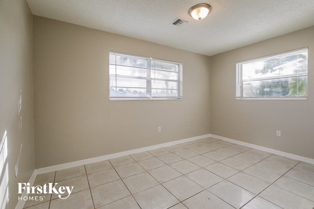 a empty living room with two windows and a tiled floor