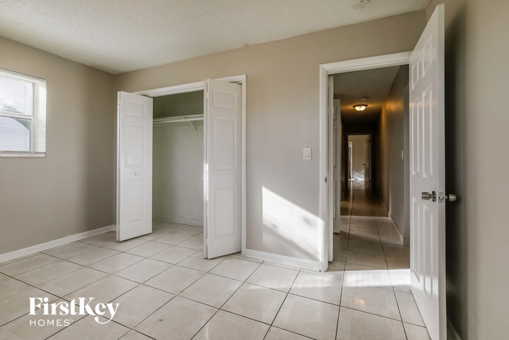 a hallway with two doors and two closets and a tiled floor