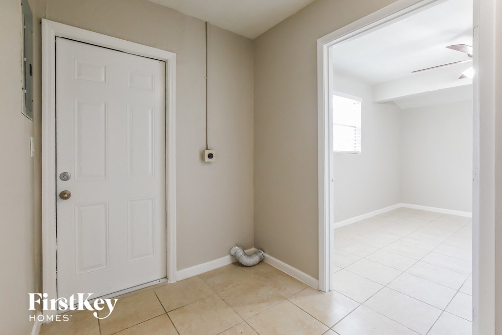 an empty room with a white door and a white tiled floor and a closet
