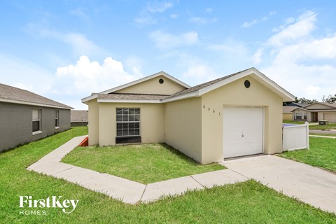 a beige house with a garage and a lawn