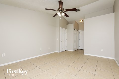 the living room and dining room with ceiling fan and tiled floors