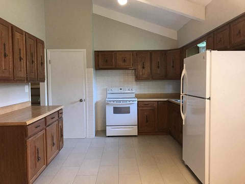 A kitchen with white appliances and wooden cabinets.