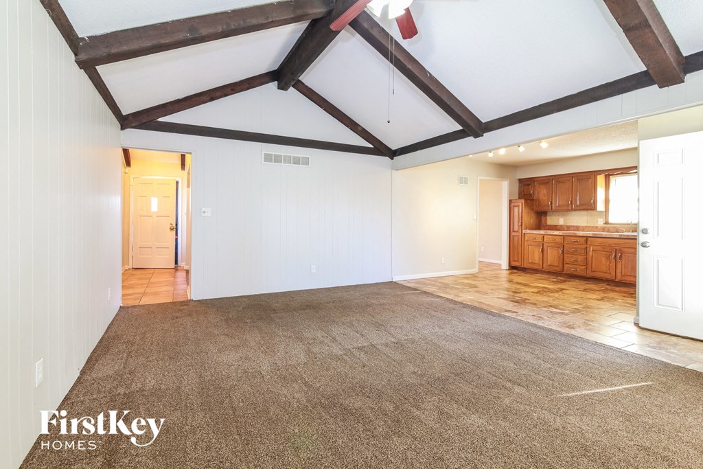 an empty living room with white walls and wood beams