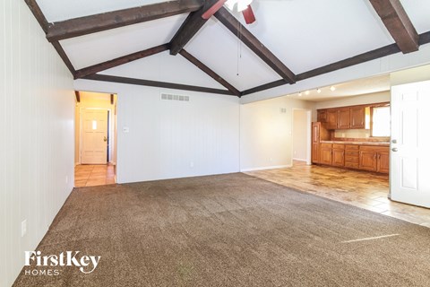 an empty living room with white walls and wood beams