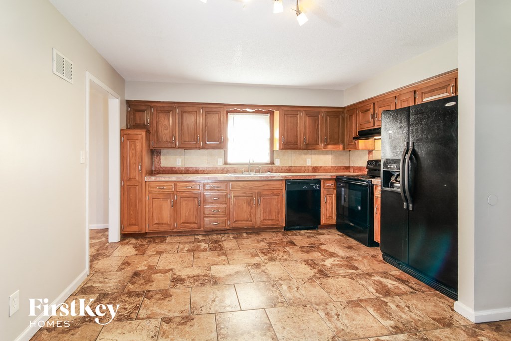 a kitchen with wooden cabinets and a black refrigerator