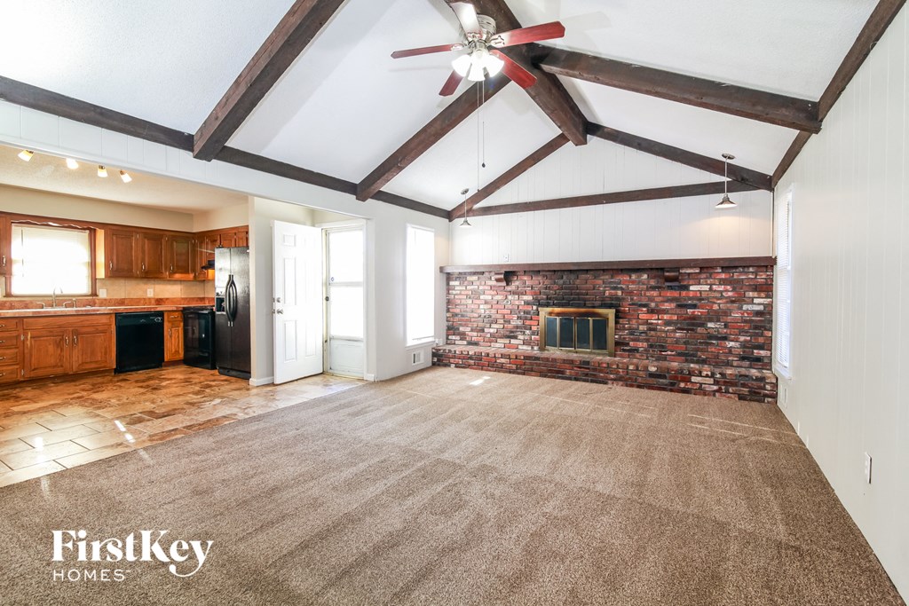 a living room with a brick fireplace and a carpeted floor