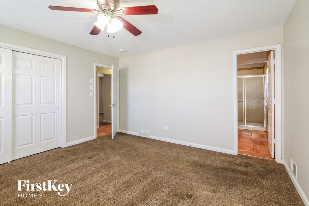 an empty living room with carpet and a ceiling fan