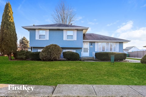 A blue house with a green lawn and a sign that says "FirstKey Homes".