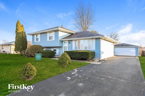 A blue house with a driveway in front of it.
