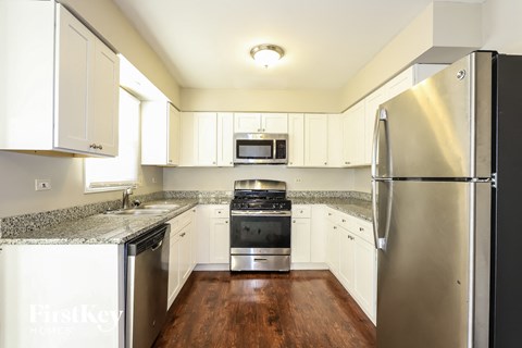 A kitchen with a stainless steel refrigerator and a stove top oven.