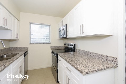 a kitchen with white cabinets and granite counter tops