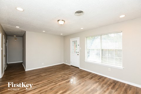 a living room with a hardwood floor and a large window