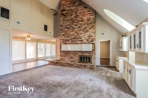 A spacious living room with a fireplace and a ceiling fan.