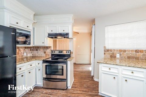 A kitchen with a black fridge, stove and oven.