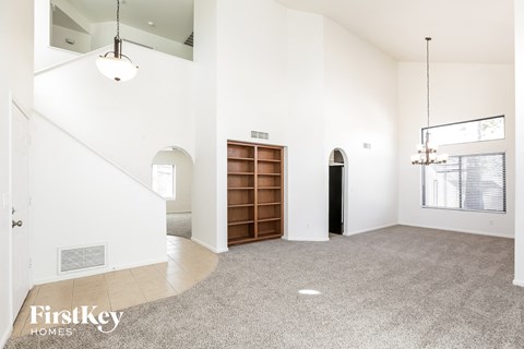 the living room and entryway of a house with a carpeted floor and white