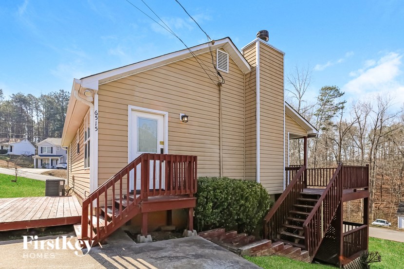 the front of a yellow house with wooden stairs and a porch