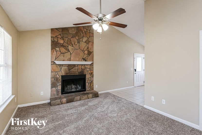 a living room with a stone fireplace and a ceiling fan