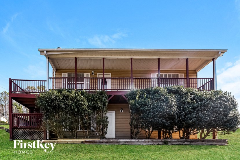 a house with a deck and trees in front of it