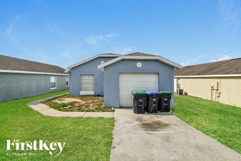 a blue house with a driveway and trash cans in front of it