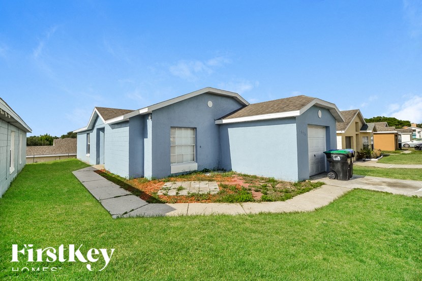 a row of small blue houses with grass and a sidewalk