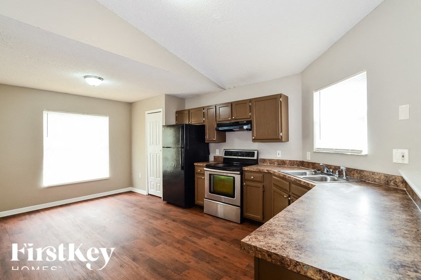 an empty kitchen with wood flooring and stainless steel appliances