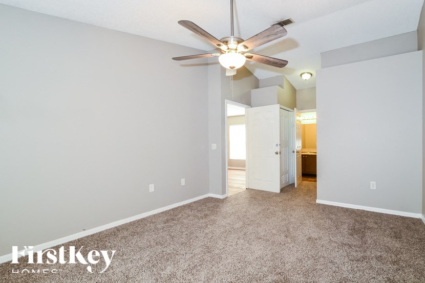 the master bedroom has a ceiling fan and a carpeted floor