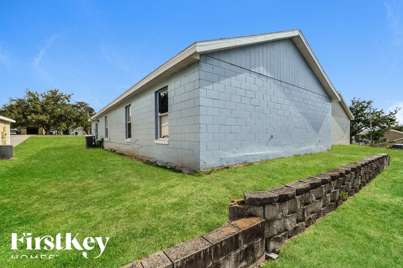a small white church with a stone retaining wall in the grass