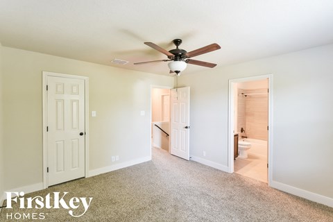 a bedroom with a ceiling fan and a door to a bathroom