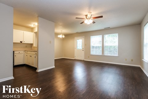 A spacious room with wooden floors and a ceiling fan.