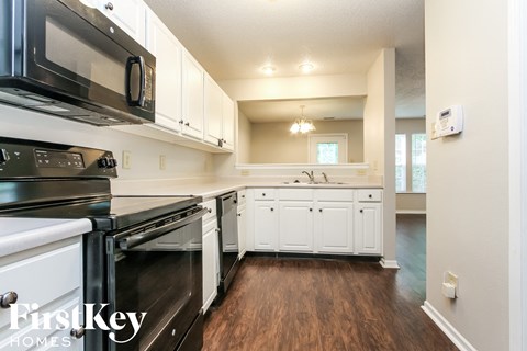 A kitchen with white cabinets and black appliances.