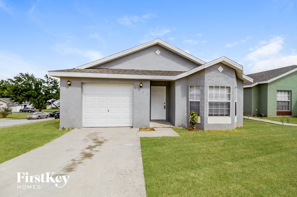 A house with a garage and a driveway in front of it.