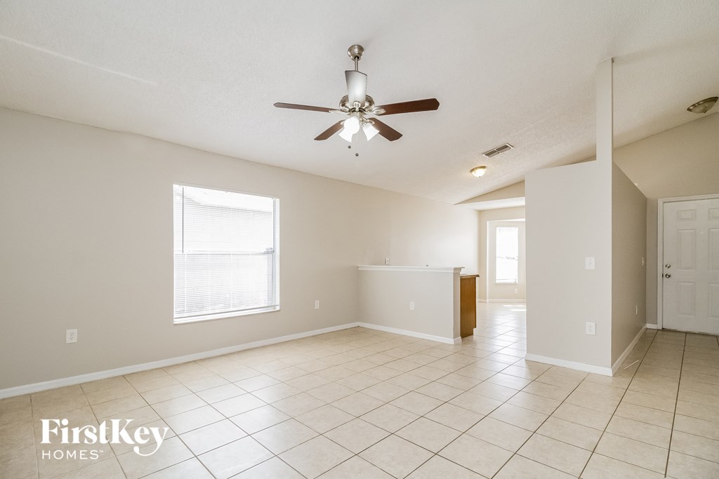 A spacious room with a ceiling fan and tiled flooring.