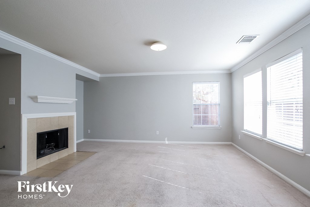 A spacious living room with a fireplace and carpeted floor.