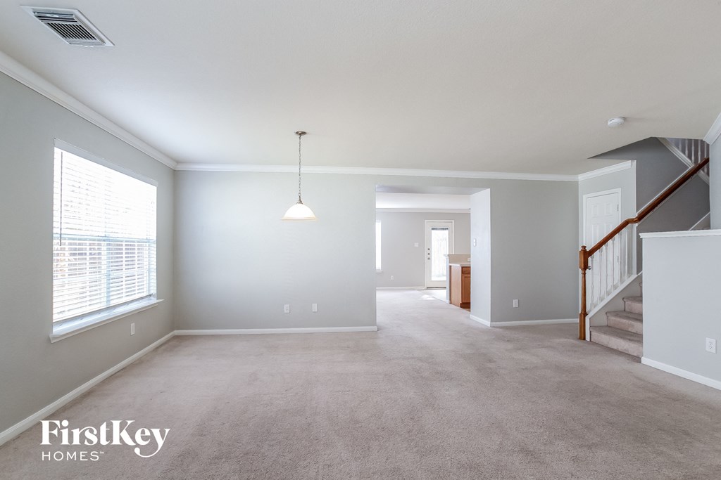 A spacious room with a staircase and a window.