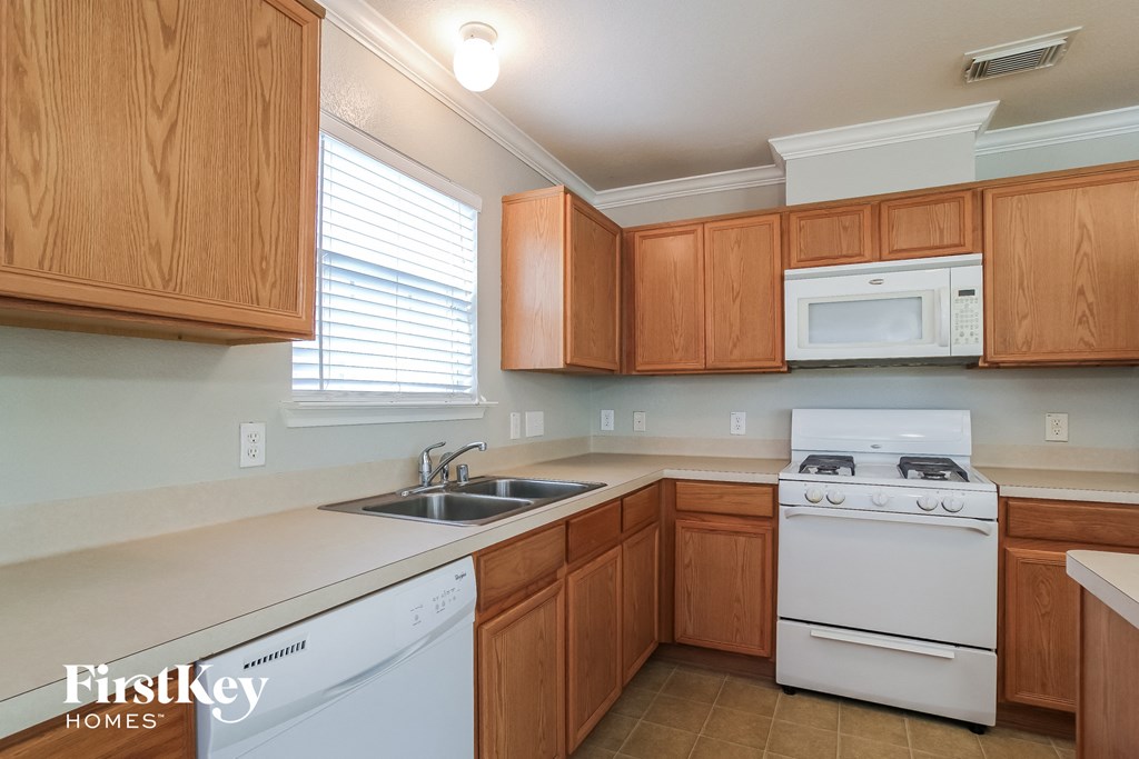 A kitchen with wooden cabinets and a white stove top oven.