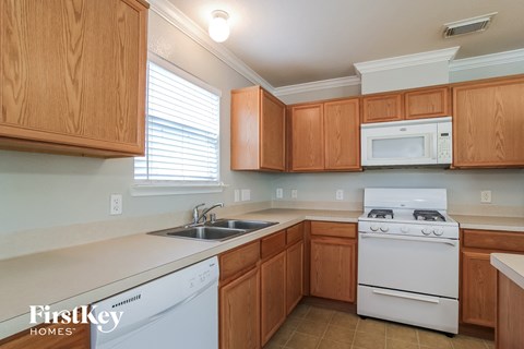 A kitchen with wooden cabinets and a white stove top oven.