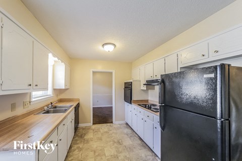 a kitchen with white cabinets and a black refrigerator