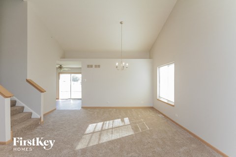 the living room and dining room of a home with white walls and carpet