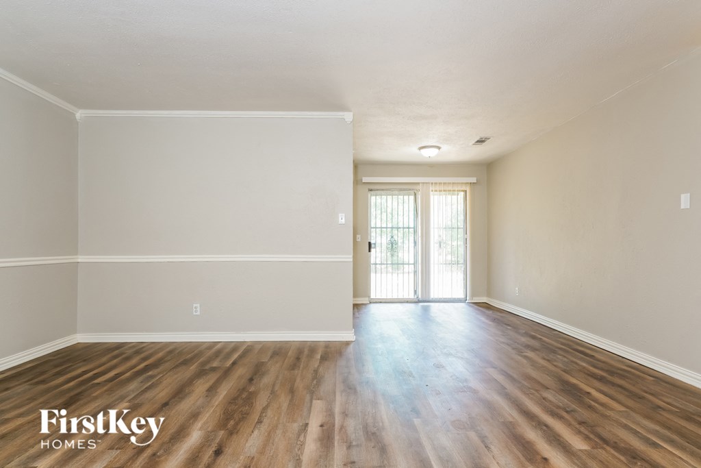 the spacious living room with wood flooring and white walls