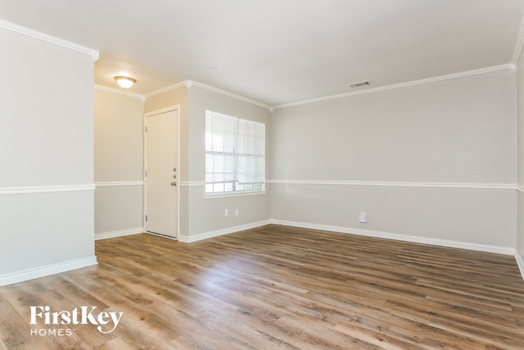 the living room of an empty house with wooden floors and a window