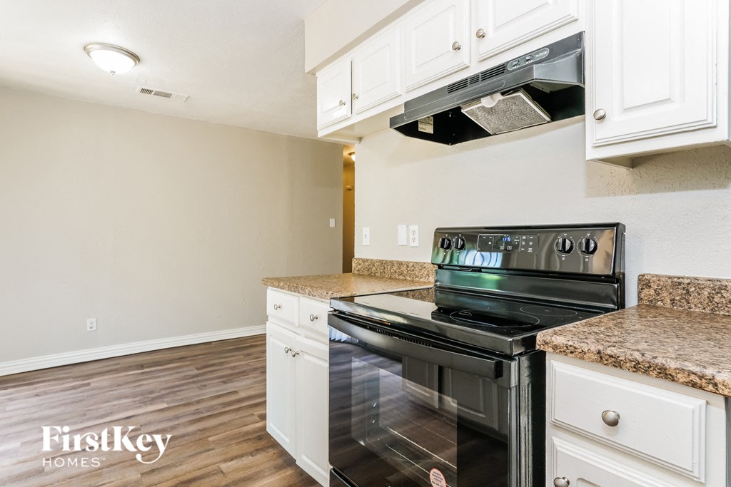 a kitchen with white cabinets and a black stove and oven