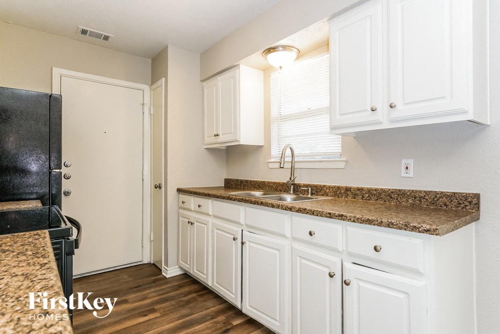 a kitchen with white cabinets and a counter top and a sink