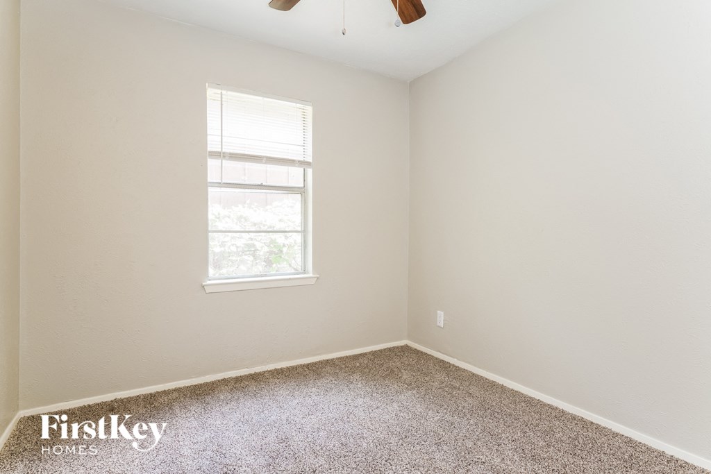 the bedroom of a small house with carpet and a window