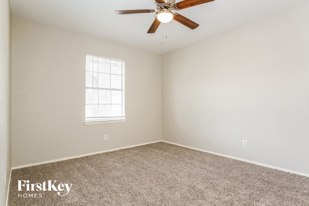 an empty room with a ceiling fan and a window