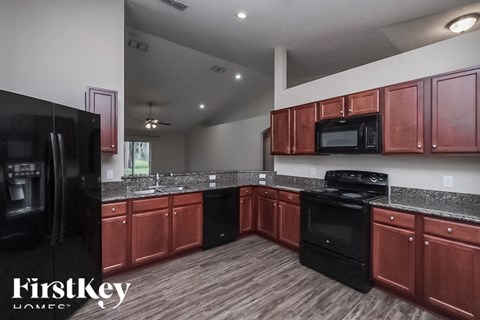 A kitchen with red cabinets and black appliances.